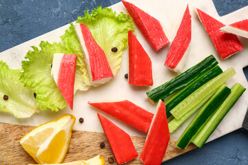 Board with tasty crab sticks on blue background, closeup © Pixel-Shot