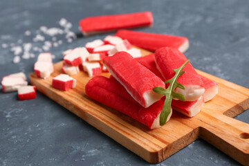 Wooden board with tasty crab sticks on green background, closeup © Pixel-Shot