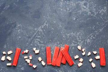 Tasty cut and whole crab sticks on green background © Pixel-Shot