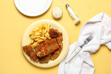 Plate of tasty fried codfish with french fries on yellow background