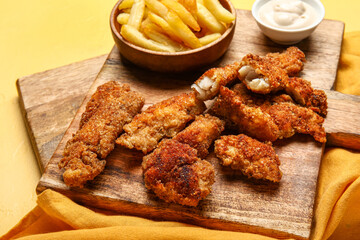 Wooden boards of tasty fried codfish on yellow background