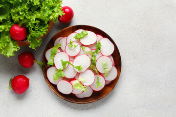 Bowls with fresh slices of radish and lettuce on white background