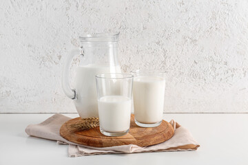 Jug and glasses with fresh milk on white background