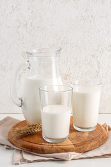 Jug and glasses with fresh milk on white background