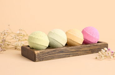 Stand with bath bombs and flowers on beige background