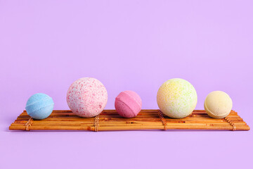 Bamboo mat with bath bombs on lilac background