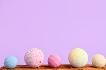Bamboo mat with bath bombs on lilac background