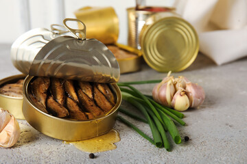 Opened tin cans with sprats in oil on grey table