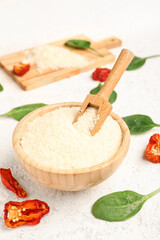 Bowl with tasty grated Parmesan cheese on light background