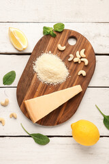 Board with tasty Parmesan cheese on light wooden background
