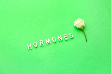 Word HORMONES with rose on green background