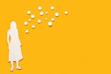 Paper female figure with hormonal pills on orange background