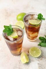 Glasses of tasty Cuba Libre cocktail on light background