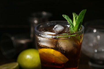 Glass of tasty Cuba Libre cocktail on dark background, closeup