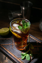Glass of tasty Cuba Libre cocktail on dark wooden background