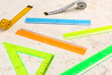 Colorful plastic rulers and measuring tapes on light grunge background