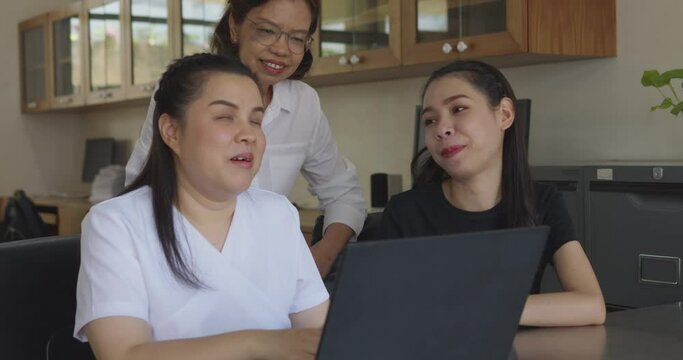 Asian women co-workers in workplace including person with blindness disability using laptop computer with screen reader program for visual impairment people. Disability inclusion at work concepts.