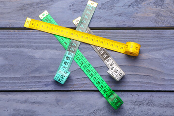 Colorful measuring tapes on blue wooden background