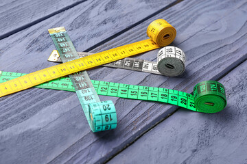 Colorful measuring tapes on blue wooden background
