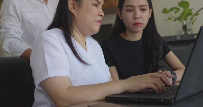 Asian women co-workers in workplace including person with blindness disability using laptop computer with screen reader program for visual impairment people. Disability inclusion at work concepts.