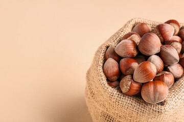 Sack bag with shelled hazelnuts on beige background
