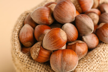 Sack bag with shelled hazelnuts on beige background