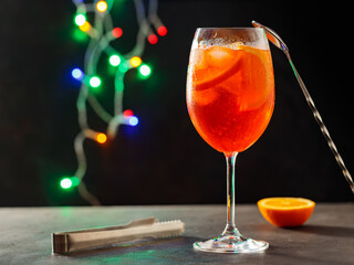 Glass of Aperol Spritz cocktail on a blurred background with colorful lights. Aperol spritz...