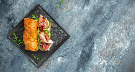 italian sandwiches with prosciutto, arugula, cucumber, Cured ham, spanish appetizer. Long banner format. top view
