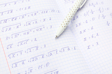 Copybook with maths formulas and pen, closeup