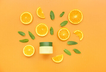 Jar of cosmetic cream with orange slices and mint on color background