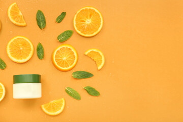 Jar of cosmetic cream with orange slices and mint on color background
