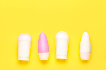 Different deodorant bottles on yellow background