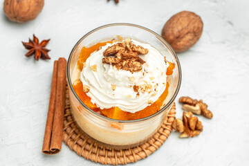 Obraz na płótnie Canvas Pumpkin parfait with nuts in glass on a light background. banner, menu, recipe place for text, top view