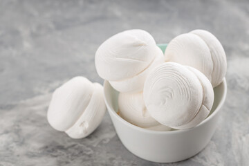 Marshmallows in bowl on a gray background. Sweet dessert zephyr marshmallows on concrete. Close up