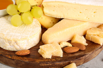 Plate with different types of cheese and grapes on table, closeup