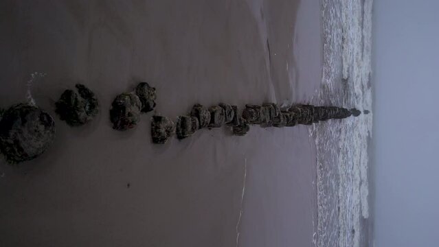 Long path from stones to sea on sandy beach with waves in Kolobrzeg, Poland.