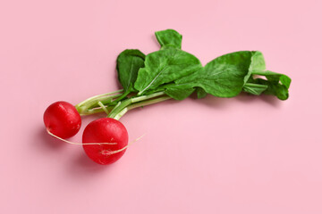 Fresh radishes with leaves on pink background