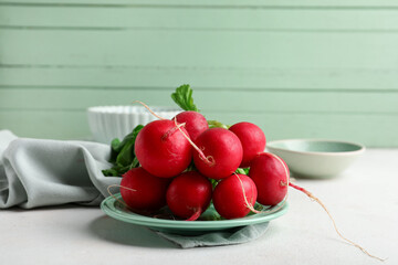 Bowls and plate of fresh radishes with leaves on light background