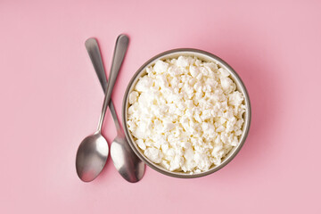 Bowl with tasty cottage cheese on pink background