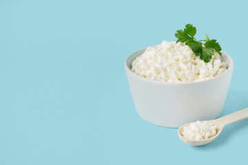 Bowl with tasty cottage cheese and parsley on blue background