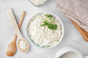Bowl with tasty cottage cheese and parsley on light background