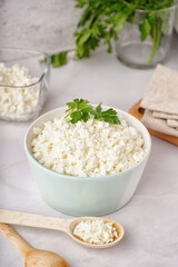 Bowl with tasty cottage cheese and parsley on light background
