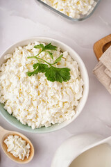 Bowl with tasty cottage cheese and parsley on light background