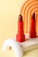 Decorative plaster podiums and lipsticks on yellow background