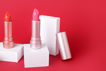 Decorative plaster podiums and lipsticks on red background
