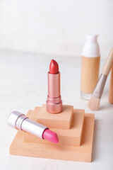 Decorative plaster podiums and lipsticks on light background