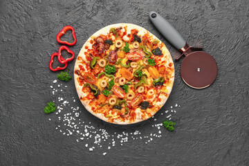 Vegetable pizza with cutter on dark background