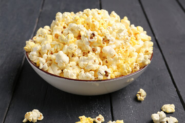 Bowl with crispy popcorn on dark wooden background