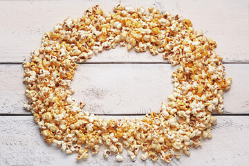 Frame made of crispy popcorn on white wooden background