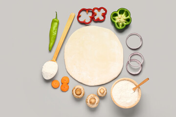 Raw dough and ingredients for preparing vegetable pie on grey background
